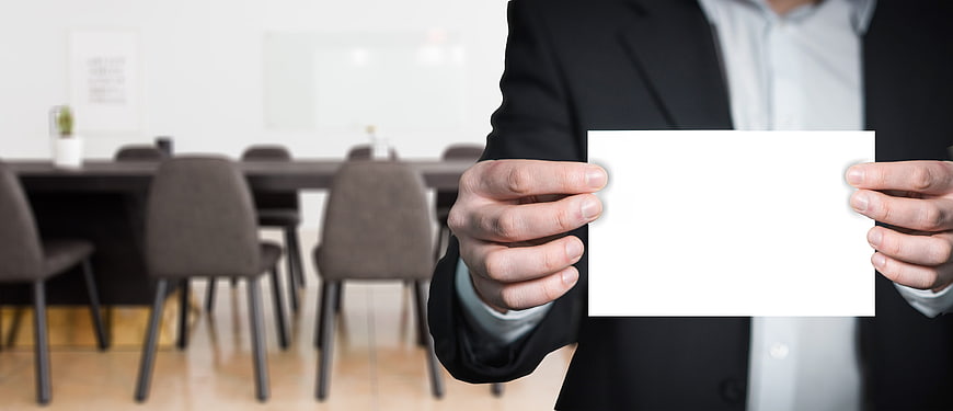 Businessman holding blank white card in modern office