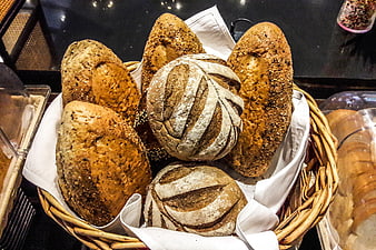 Assorted artisan bread loaves in a wicker basket at a bakery