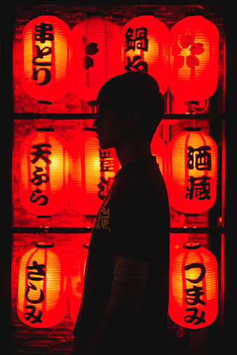 Silhouette of man in profile against glowing red Japanese lanterns