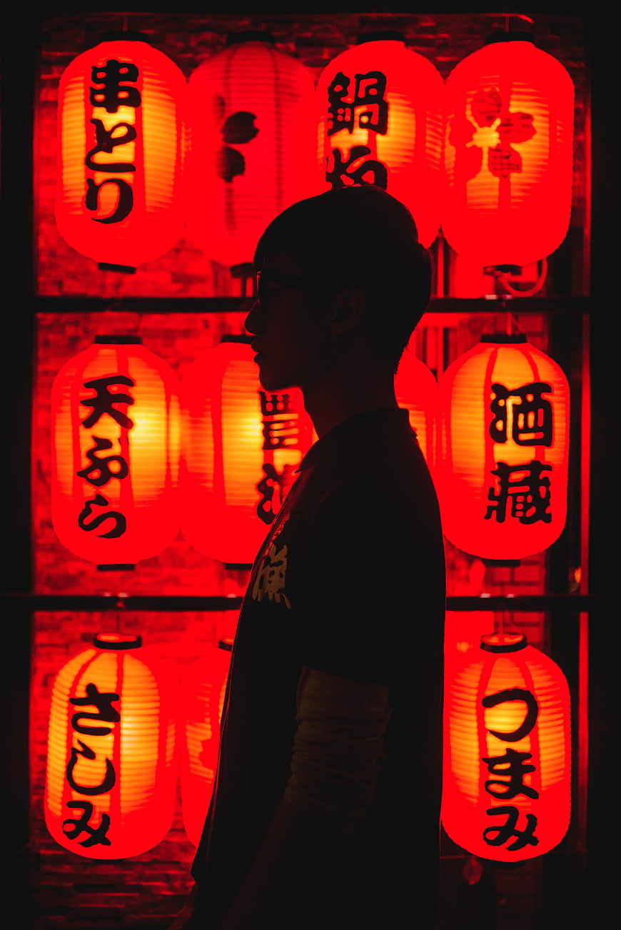 Silhouette of man in profile against glowing red Japanese lanterns