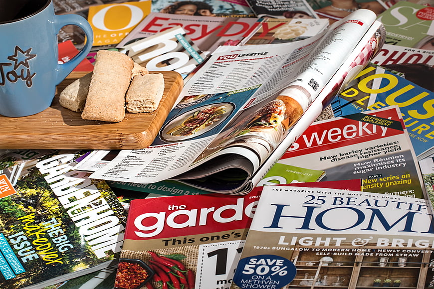 Stack of Lifestyle Magazines with Coffee and Biscuits on Wooden Board