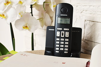 Black Siemens Cordless Phone on Desk with Orchids