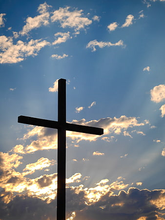 Silhouette of a Cross Against a Dramatic Blue Sky with Sun Rays