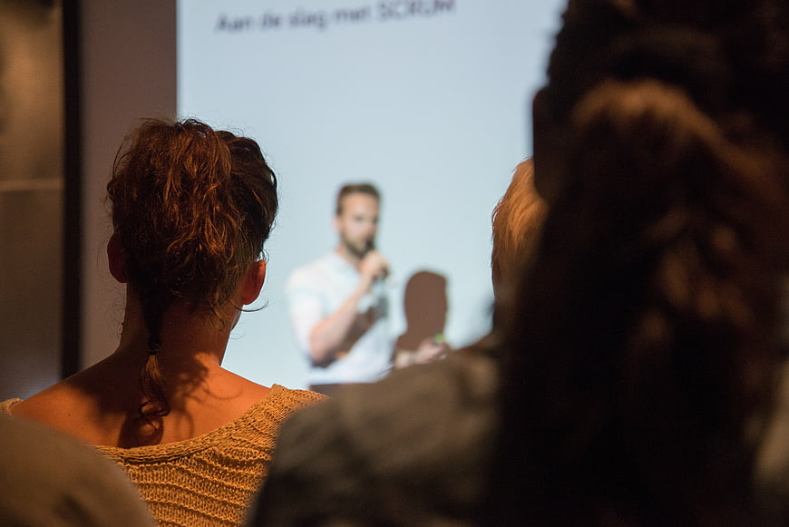Audience watching a man present at a corporate conference