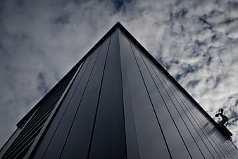 Low angle view of modern dark building against cloudy sky