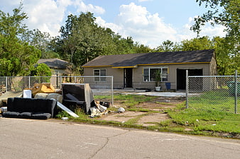 Abandoned house with discarded furniture and trash in front yard