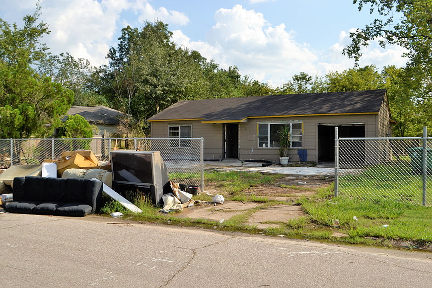 Abandoned house with discarded furniture and trash in front yard