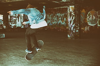 Skateboarder performing trick in graffiti-covered skatepark