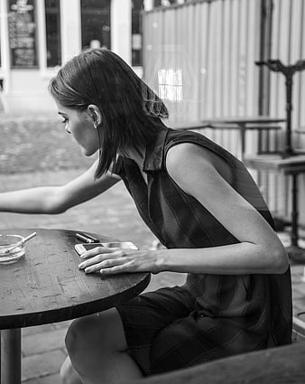 Young woman smoking at outdoor cafe table in black and white