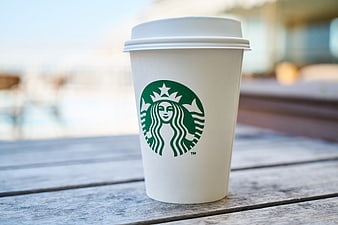 Starbucks coffee cup on wooden table outdoors