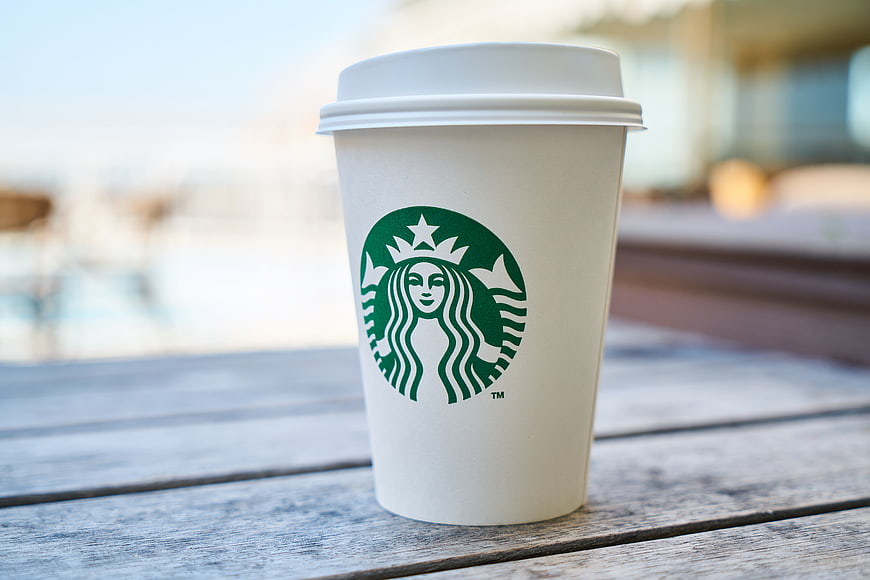 Starbucks coffee cup on wooden table outdoors