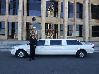 Chauffeur in Suit Standing by White Stretch Limousine