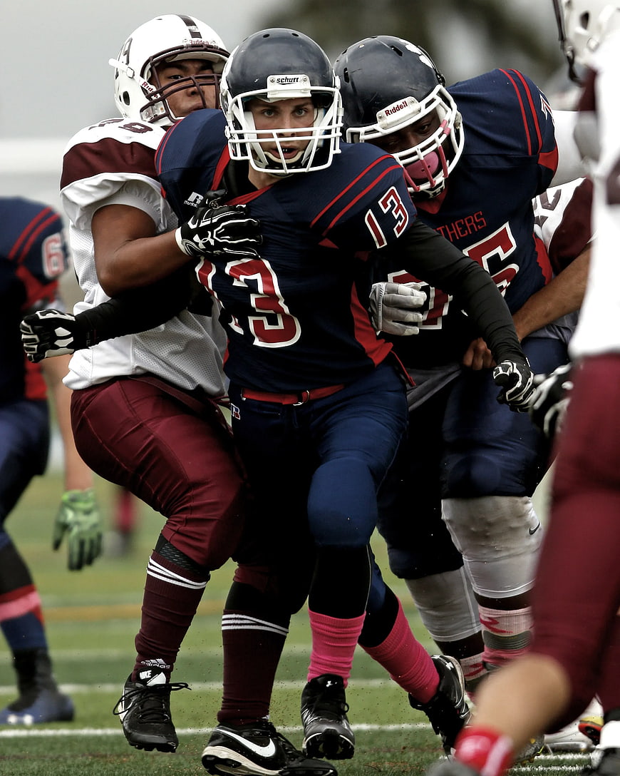 American Football Player Tackled by Opponents on Field