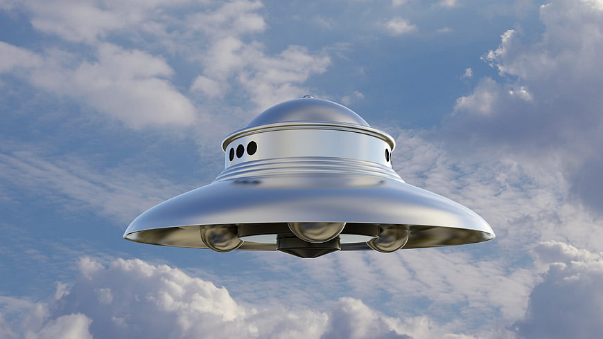 Silver UFO Saucer Flying In Blue Cloudy Sky