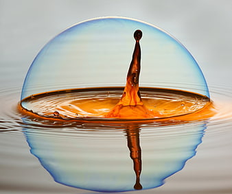 Macro soap bubble with amber liquid splash and reflection