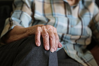 Close-up of elderly woman's wrinkled hands resting on knee