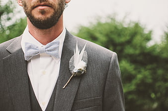 Groom in Gray Suit with Striped Bow Tie and Feather Boutonniere