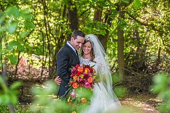 Happy Bride and Groom Embracing in Forest with Bouquet