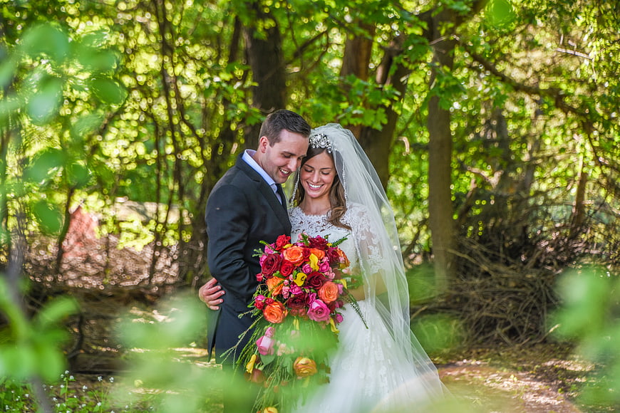 Happy Bride and Groom Embracing in Forest with Bouquet