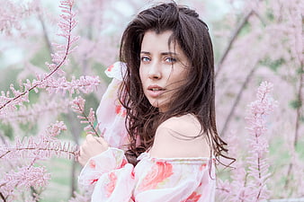 Young brunette woman in floral dress among pink flowers