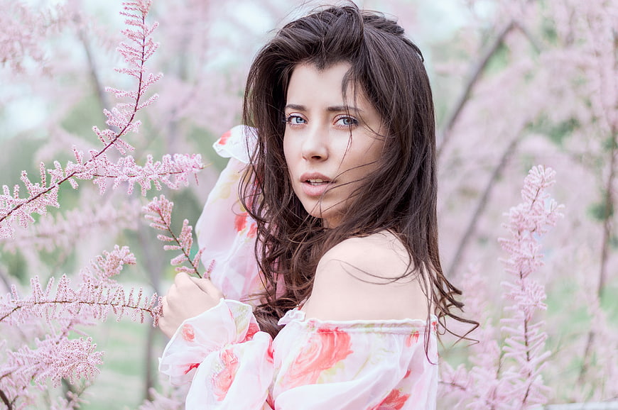 Young brunette woman in floral dress among pink flowers