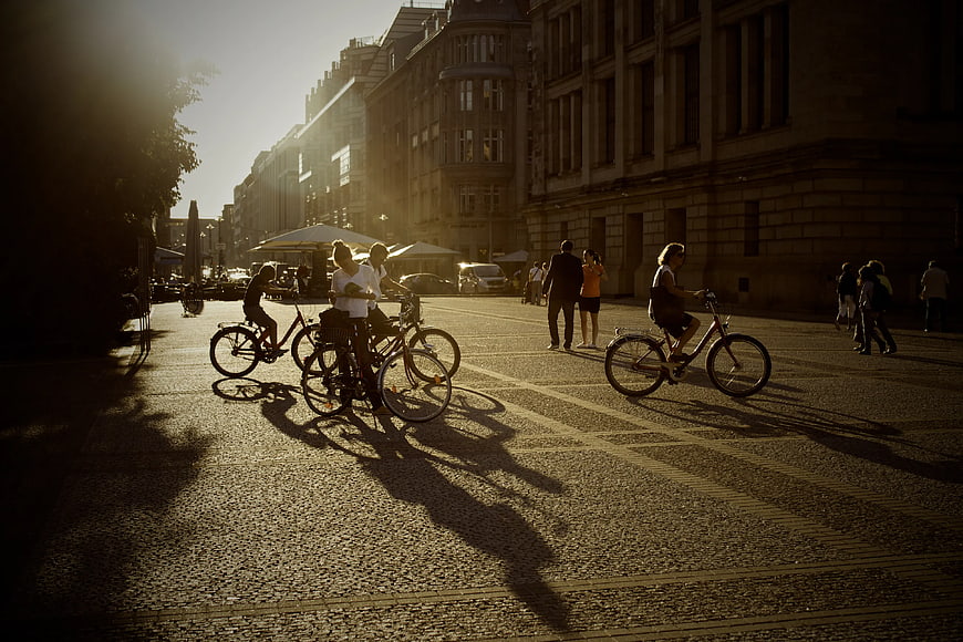 Cyclists Riding on Cobblestone Street in Golden Hour Sunlight