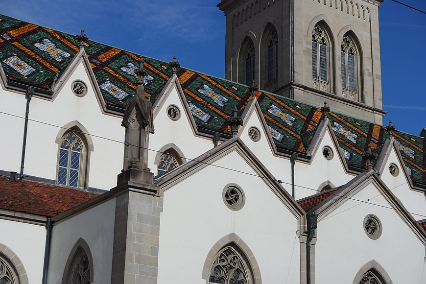 Gothic church facade with colorful tiled roof and tower