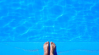 Relaxing feet at the edge of a blue swimming pool