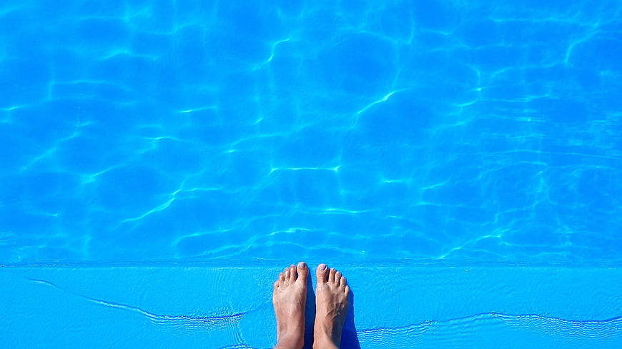 Relaxing feet at the edge of a blue swimming pool