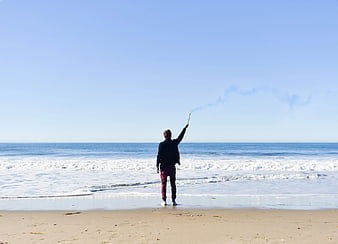 Man Standing on Beach Holding Smoldering Stick