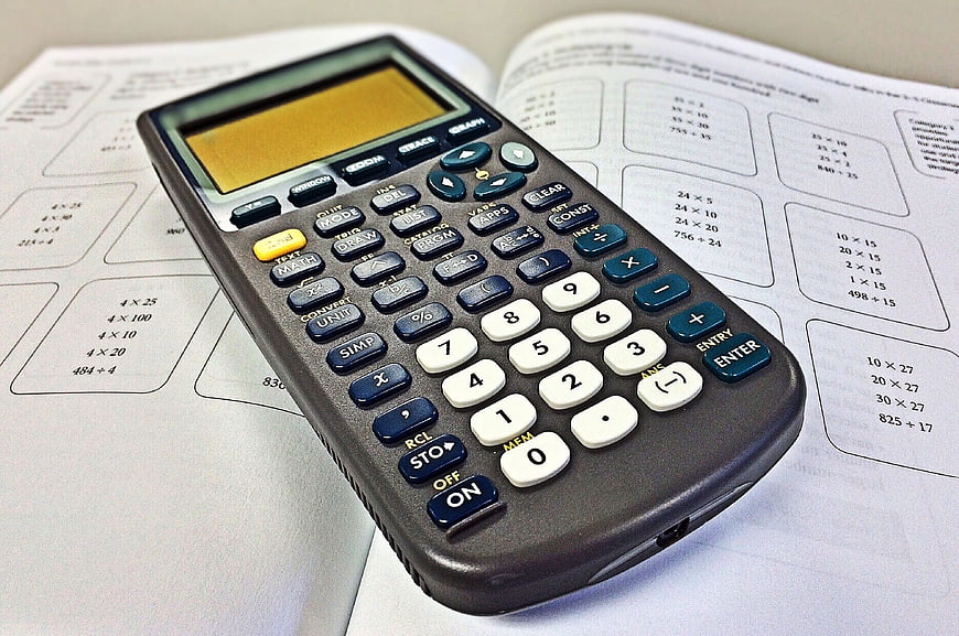 Scientific calculator on open math textbook with multiplication exercises