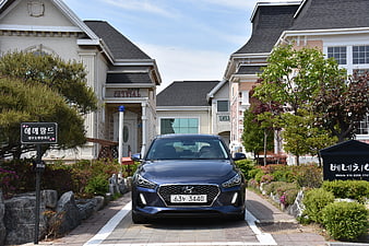 Blue Hyundai i30 parked in front of modern houses