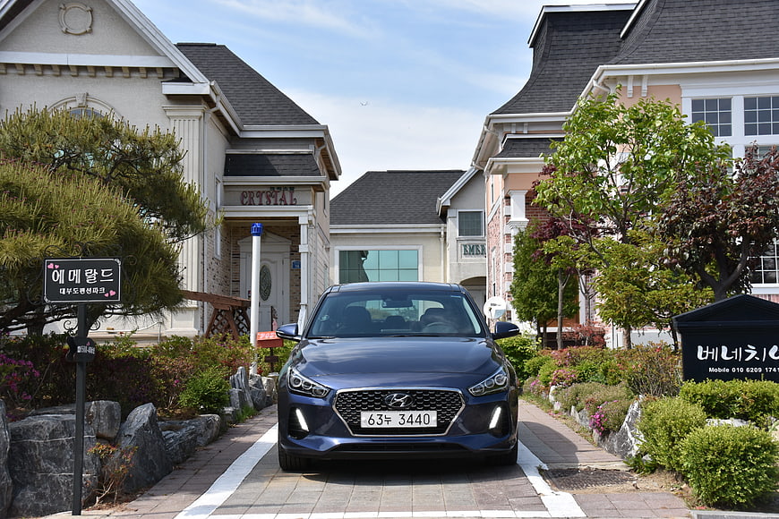 Blue Hyundai i30 parked in front of modern houses