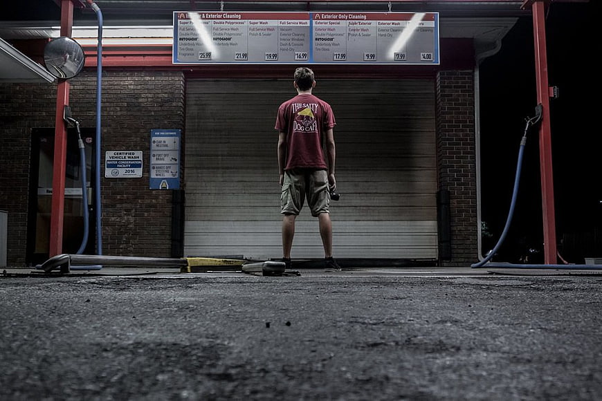 Man Standing Alone at Closed Car Wash at Night