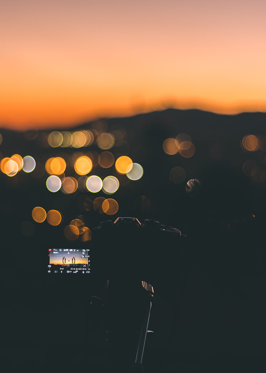 Camera on Tripod Capturing Sunset Bokeh Cityscape