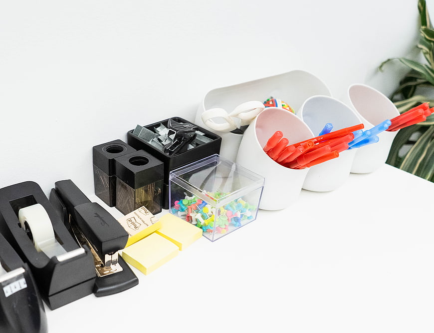 Organized office supplies on white desk with copyspace