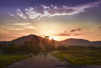 Golden Sunset Over Rural Landscape With Walking People