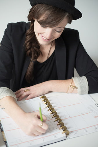 Smiling Woman Writing in Planner with Pencil