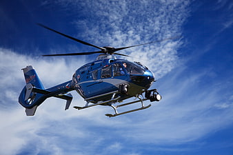 Blue Police Helicopter Flying in Blue Sky with Clouds