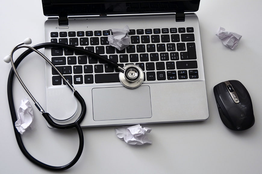 Stethoscope on laptop keyboard with crumpled paper
