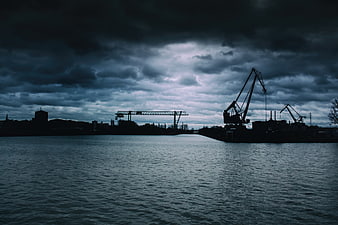 Silhouette of industrial cranes at a port under stormy sky