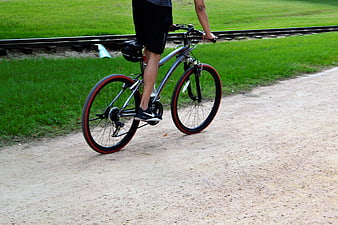 Man Riding Bicycle On Gravel Path Near Train Tracks