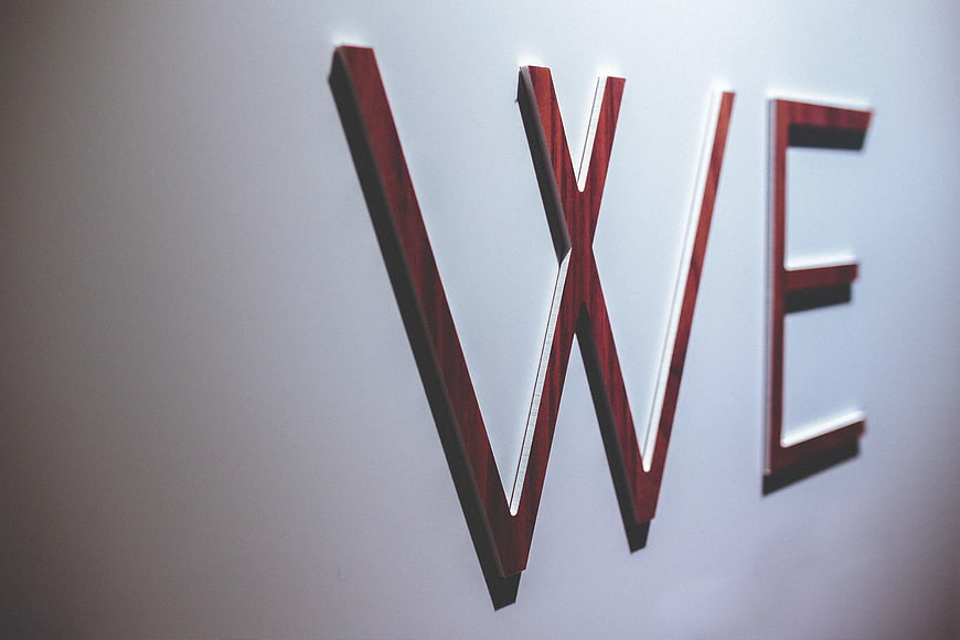 Wooden WE letters on white wall with copyspace