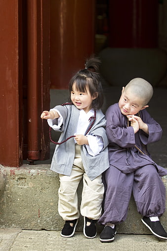 Cute Children in Traditional Monk Robes Sitting on Stone Step