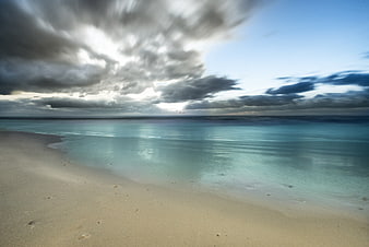 Dramatic long exposure beach with smooth water and cloudy sky