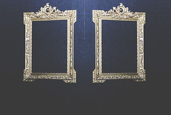 Two ornate gold picture frames on dark blue textured wall