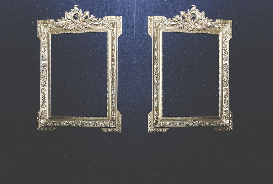 Two ornate gold picture frames on dark blue textured wall