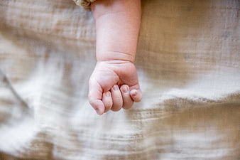 Close-up of a newborn baby's hand on beige fabric