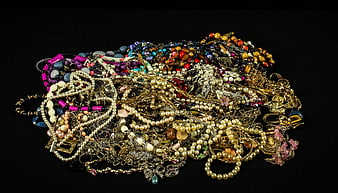 Tangled pile of vintage jewelry, pearls, and colorful beads on black background