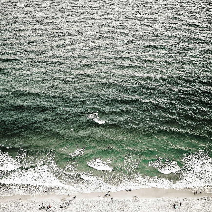 Aerial View of Green Ocean Waves Crashing on Sandy Beach